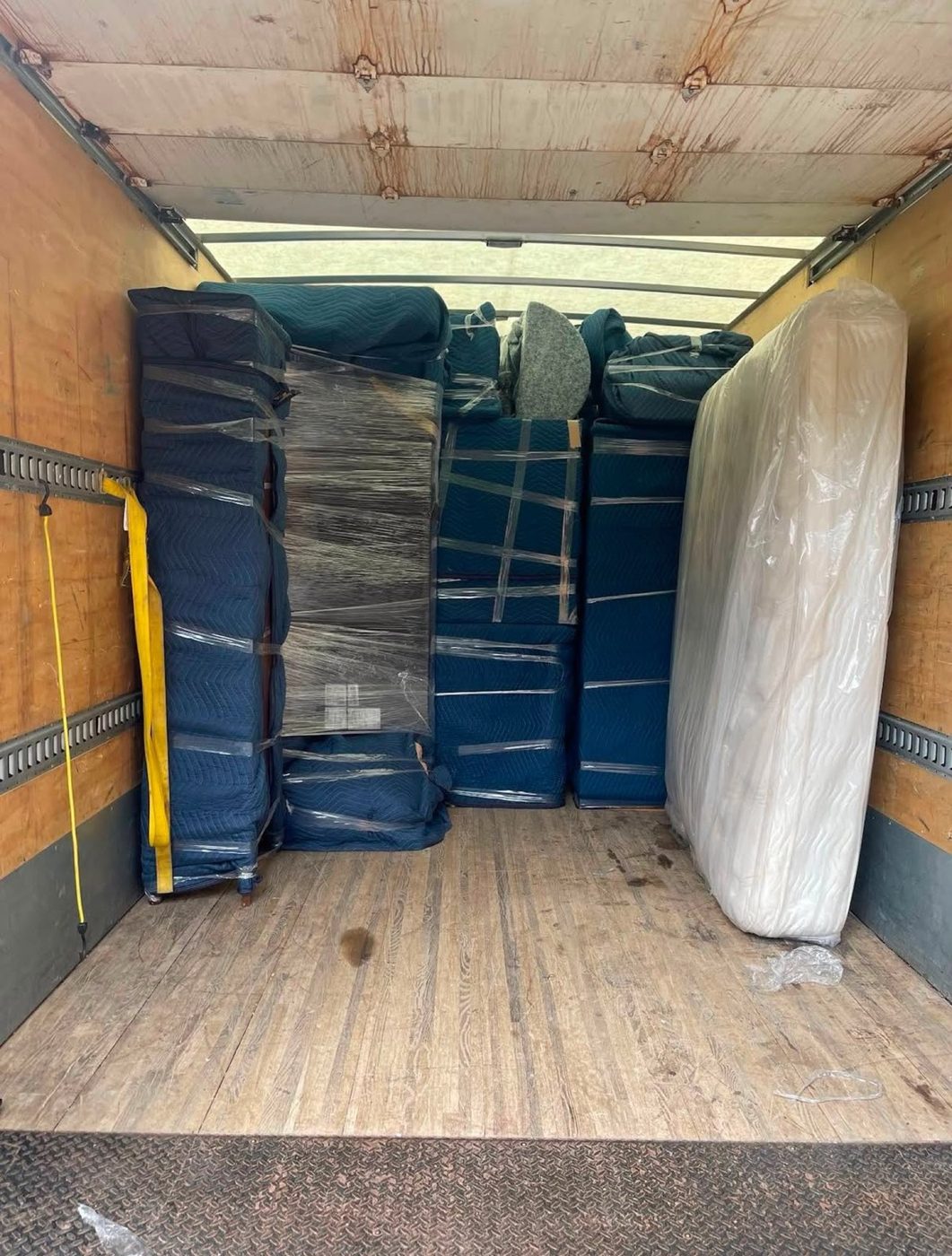 Inside a truck, with covered furniture and a wrapped mattress.