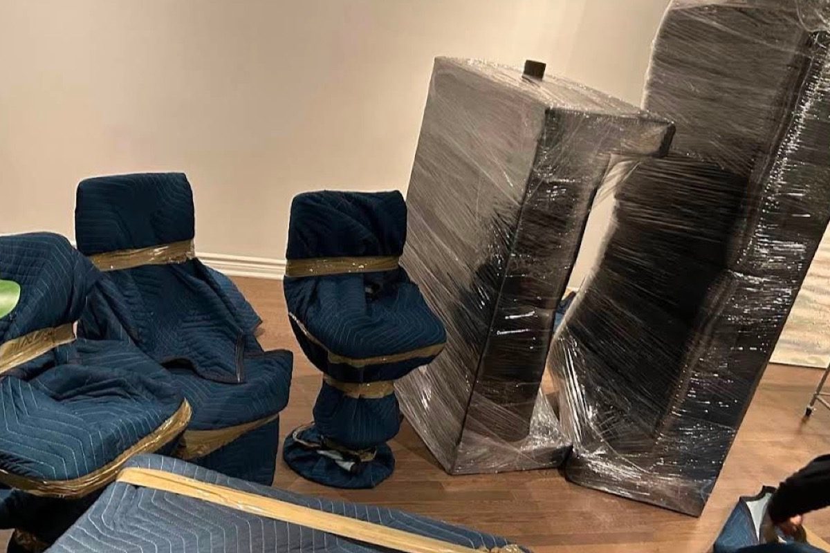 Chairs under blue pads and a sofa under plastic wrap.