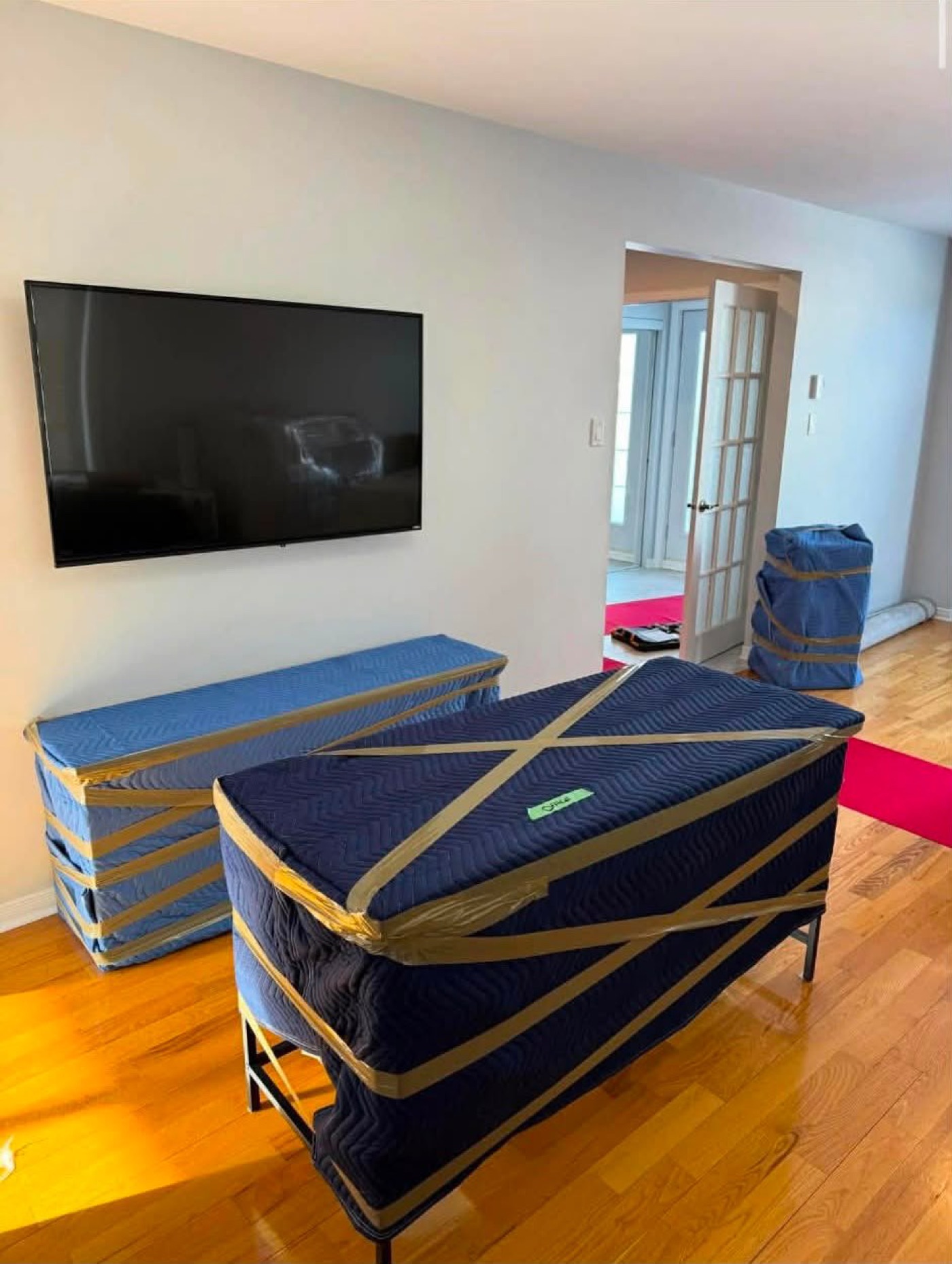 A piano and a dresser covered with pads in a living room.