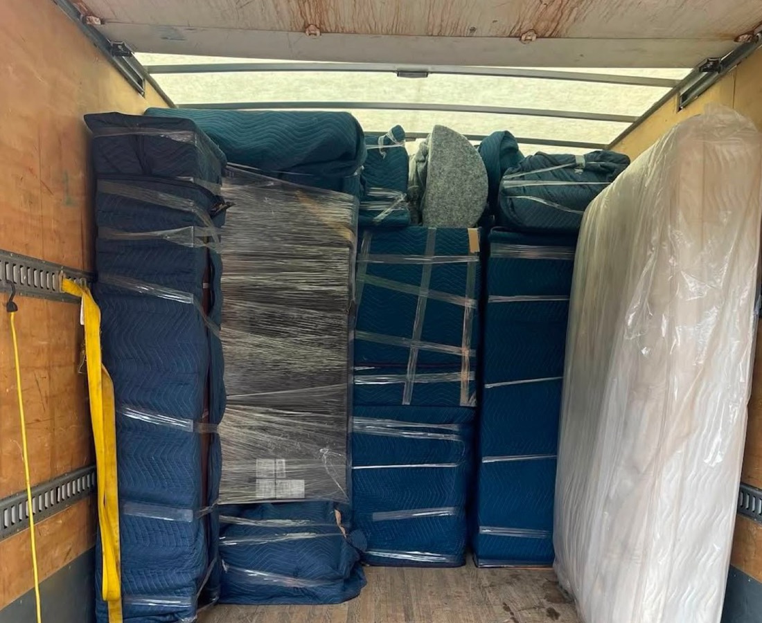 Meubles sanglés et matelas emballé contre la paroi du camion.